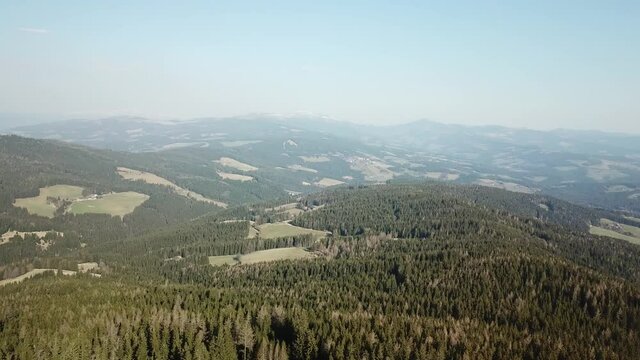A panoramic, drone capture of a forest in Austrian Alps. Early spring in Alps. High Alpine peaks covered with snow. The nature wakes up after hibernation. Steep and dangerous climbing. Adventure
