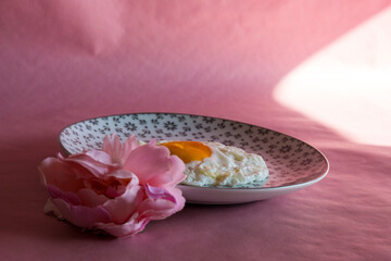 Homemade meal, Organic tasty cooked eggs for healthy breakfast on pink background, fancy ceramic plates, and flowers in a vintage artistic composition. Simple food composition