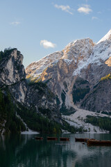 A view of the lake Pragser Wildsee in the Dolomites with a chain of boats, mountains and woods in autumn in South Tyrol, Italy.