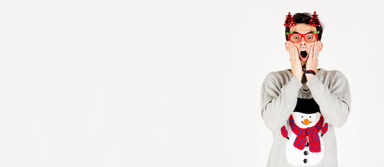 Young surprised man in Christmas sweater with party glasses on white background