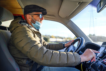 man driving with mask looking at his phone