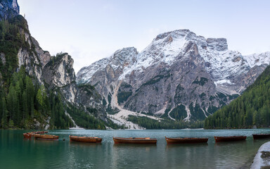 A panoramic view of the lake Pragser Wildsee in the Dolomites with a chain of boats, mountains and woods in autumn in South Tyrol, Italy.