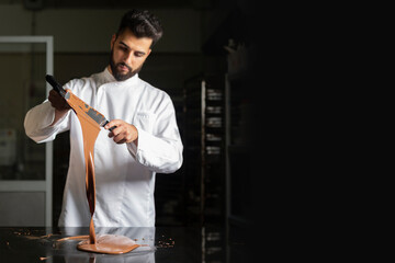 Pastry chef working on tempering chocolate on marble table