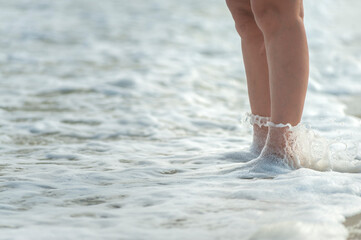 Feminine barefoot legs covered with sea foam