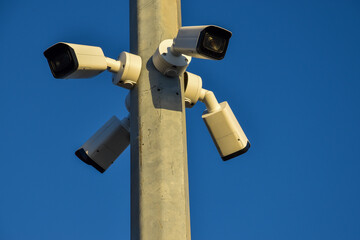 Public security cameras for recording on the street. 
Surveillance cameras recording citizens. White cameras mounted on a metal pole.