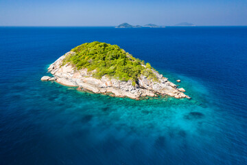 Aerial view of a remote, tiny tropical island in a clear, warm ocean