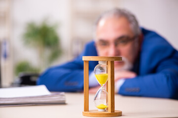 Old male employee businessman in time management concept