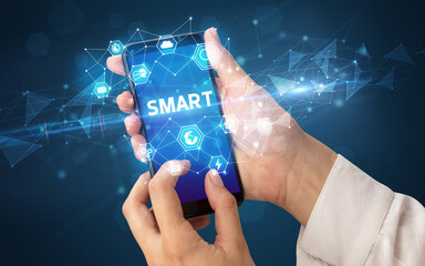 Female hand holding smartphone with SMART inscription, modern technology concept