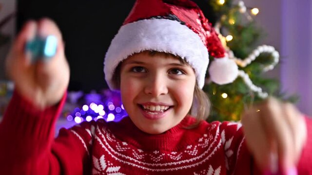 Happy little girl decorates a Christmas tree has fun and dances with Christmas balls. Child in the house decorated for Christmas. High quality 4k footage