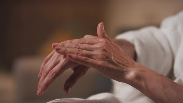 Close-up of unrecognizable middle-aged female hands in selective focus with soft and smooth cream with moisturizing effect