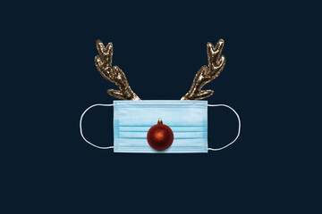Christmas background with medical mask, Santa Reindeer antlers and Christmas ball