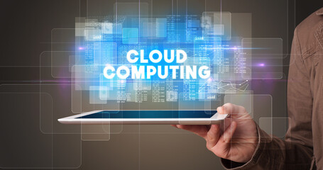 Young business person working on tablet and shows the inscription: CLOUD COMPUTING