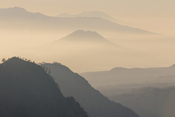 Mountain range with visible silhouettes through the morning yellowish fog.