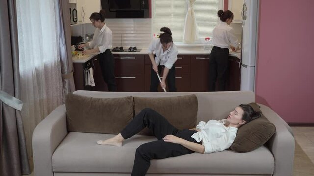 Woman doing housework concept. A very tired woman is resting on the couch after hard work in the kitchen. The cloned girl does three jobs at the same time