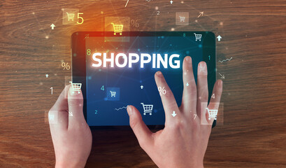 Close-up of a hand holding tablet with SHOPPING inscription, online shopping concept