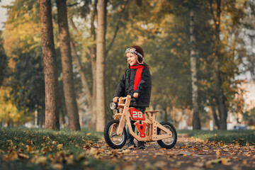 little kid riding a balance bike in outerwear in autumn