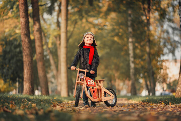Fototapeta premium little kid riding a balance bike in outerwear in autumn