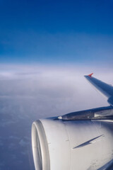 The passenger plane transports passengers in the air, looking out from the glass window of the plane while traveling, and the wing flies in the beautiful clouds of the sky.