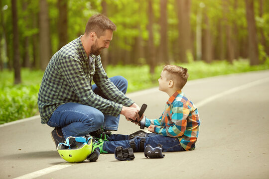 Father and son in the open air, preparing for roller skating. Father's Day.