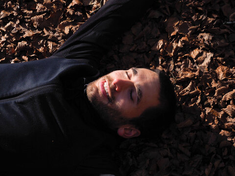 young man lying on a forest floor 