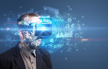 Businessman looking through Virtual Reality glasses with BIG DATA inscription, innovative technology concept