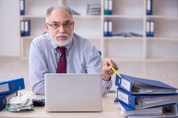 Old male accountant in budget planning concept in the office