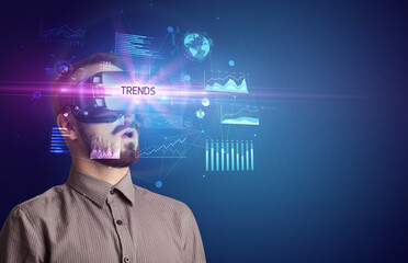 Businessman looking through Virtual Reality glasses with TRENDS inscription, new business concept