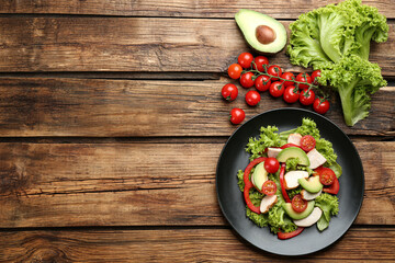 Delicious fresh chicken salad and vegetables on wooden table, flat lay. Space for text