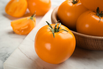 Ripe yellow tomatoes on white marble board, closeup