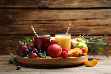 Delicious colorful juices in glasses and fresh ingredients on wooden table