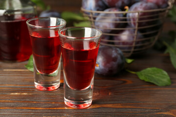 Delicious plum liquor on wooden table. Homemade strong alcoholic beverage