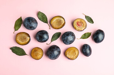 Delicious ripe plums on pink background, flat lay