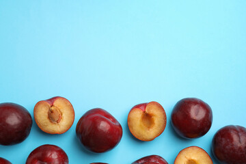 Fototapeta na wymiar Delicious ripe plums on light blue background, flat lay. Space for text