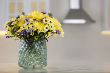 Vase with beautiful chrysanthemum flowers on table in kitchen, space for text. Interior design