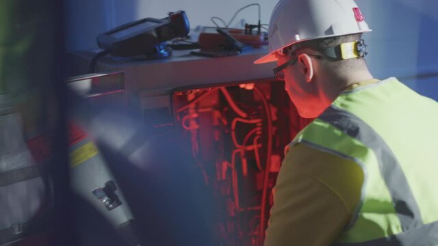 Confused service engineer works with broken electrical equipment of an industrial robot cabinet