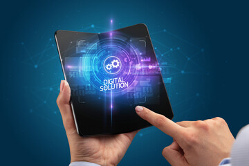 Businessman holding a foldable smartphone with APPLICATION inscription, new technology concept DIGITAL SOLUTION