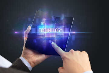 Obraz premium Businessman holding a foldable smartphone with TECHNOLOGY inscription, new technology concept