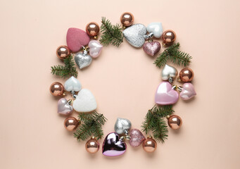 Beautiful festive wreath made of different Christmas balls and fir tree branches on beige background, top view