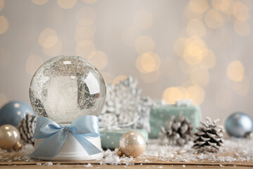 Beautiful empty snow globe and Christmas decor on table against blurred festive lights. Space for...