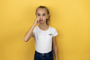 Young beautiful child girl standing over isolated yellow background mouth and lips shut as zip with fingers. Secret © Irene