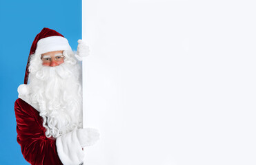 Fototapeta na wymiar Santa Claus holding empty banner on light blue background