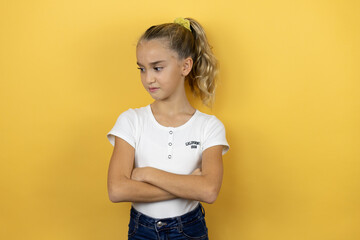 Young beautiful child girl standing over isolated yellow background thinking looking tired and bored with crossed arms