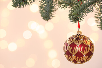 Beautiful holiday bauble hanging on Christmas tree against blurred lights, closeup. Space for text