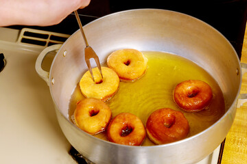 Baker flips and fries donuts with hole in hot oil.