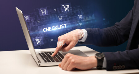 Businessman working on laptop with CHECKLIST inscription, online shopping concept