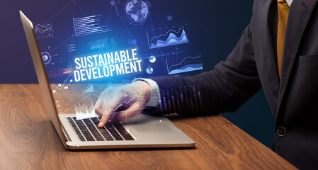 Businessman working on laptop with SUSTAINABLE DEVELOPMENT inscription, new business concept
