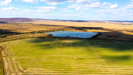 A green field and a blue lake were photographed from a drone in good weather