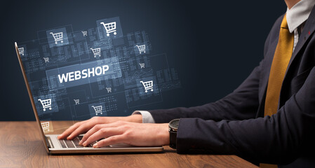 Businessman working on laptop with WEBSHOP inscription, online shopping concept