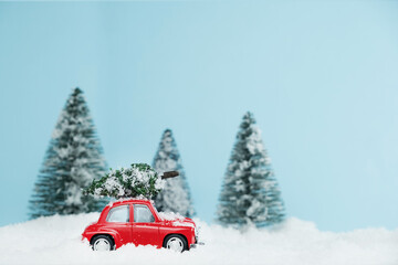 New Year red car with Christmas tree in snowy forest. Space for text. Happy New Year card concept