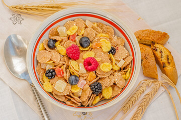 Healthy breakfast. Sunlight, dry muesli, spikelets, candied fruits and ripe summer berries. Close-up, top view. On a white background. Selective focus.